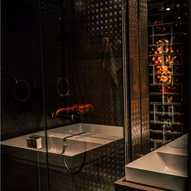 A modern bathroom with a glass shower and a stylish sink. The lighting creates a cozy atmosphere.