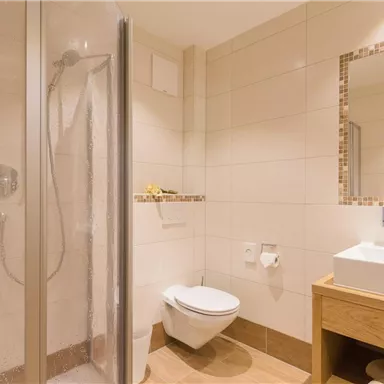 A modern bathroom with a shower and a wooden sink. It features bright walls and a straightforward design.