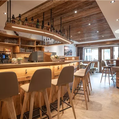 A cozy bar with wooden shelves and modern interior. Bright lighting creates an inviting atmosphere.