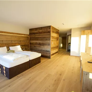 A modern hotel room with wooden details and two beds. The room is bright and welcoming, featuring a large window and minimalist furniture.