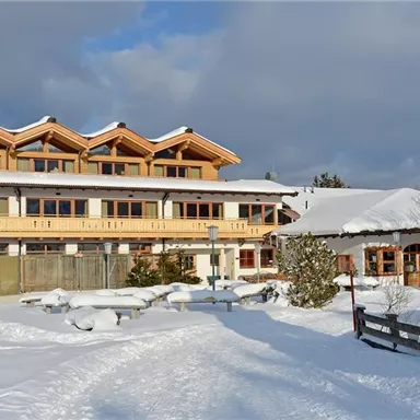 A cozy hotel in the snow with lots of wood and large windows. The surroundings are winter beautiful and the landscape is covered in snow.