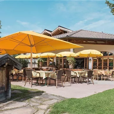 An inviting restaurant with sun umbrellas and cozy terrace seating. The surroundings are green and invite you to linger.