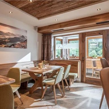 A cozy café with wooden furniture and a view of nature. Large windows provide plenty of daylight and create an inviting atmosphere.
