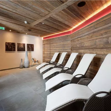 A relaxing spa area with modern loungers and wooden-paneled walls. Soft lighting creates a serene atmosphere.