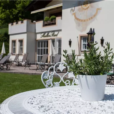 Ein schöner Außenbereich mit Liegen und Sonnenschirmen. Im Vordergrund steht ein Tisch mit einem Blumentopf.