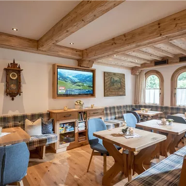 A cozy restaurant with wooden furniture and a rustic ambiance.  
Large windows provide plenty of daylight and an inviting atmosphere.