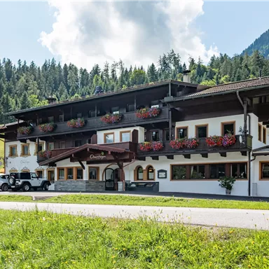 A charming hotel in alpine style with blooming balconies. Surrounded by green meadows and majestic mountains.