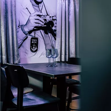 A stylish room with a table and chairs. On the wall hangs a picture of a famous musician with a camera.