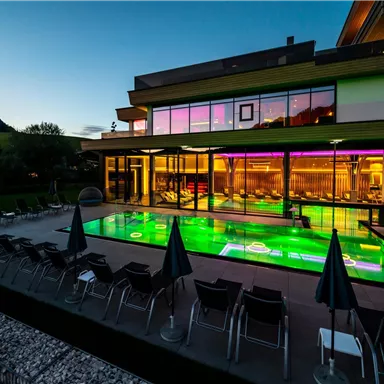 A modern swimming pool in a stylish building at night. Colorful lights reflect in the water and create a relaxing atmosphere.