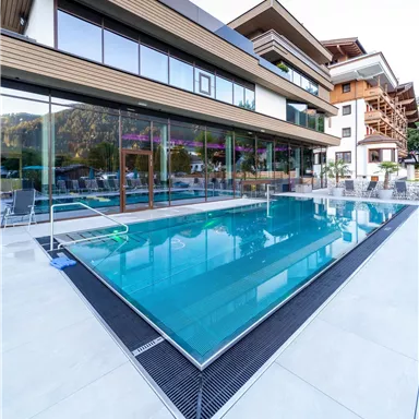 A modern building with large windows and a clear pool. The surroundings appear inviting and stylish.