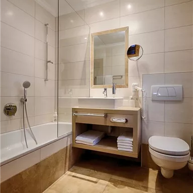 A modern bathroom with a bathtub and a sink. Bright tiles and a large mirror create an inviting atmosphere.