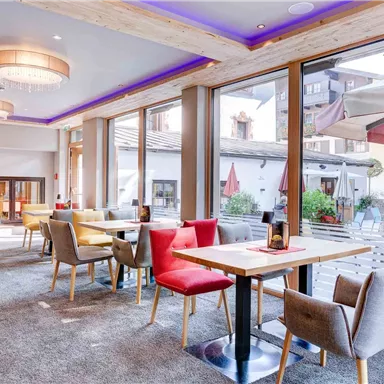 A modern restaurant with large windows and plenty of natural light. The decor consists of comfortable chairs and stylish tables.
