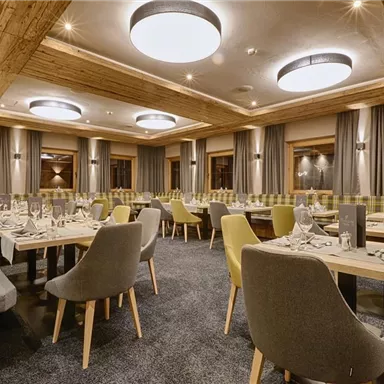An elegant restaurant with wooden decor and a cozy atmosphere. Tables are set for guests and the lighting creates a warm ambiance.