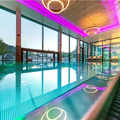 An elegant wellness area with a pool and modern lighting elements. Large windows offer a beautiful view of the surroundings.