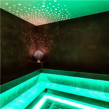 A modern wellness area with soft green lights and a stylish light accent on the wall. The cozy atmosphere invites relaxation.