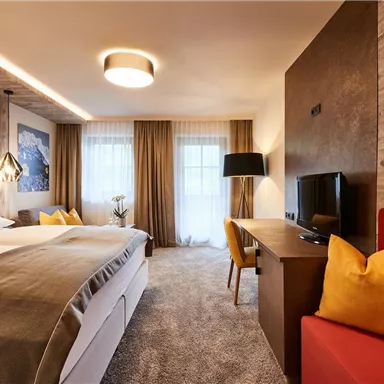 A modern hotel room with a comfortable double bed and stylish furniture. Large windows let in plenty of light and create an inviting atmosphere.