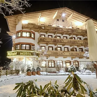A hotel building in a winter scene at night, surrounded by snow. The lighting creates a cozy atmosphere.