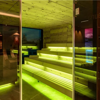 A modern wellness area with light green lights and wooden paneling. The room is designed in a minimalist style and conveys a sense of relaxation.