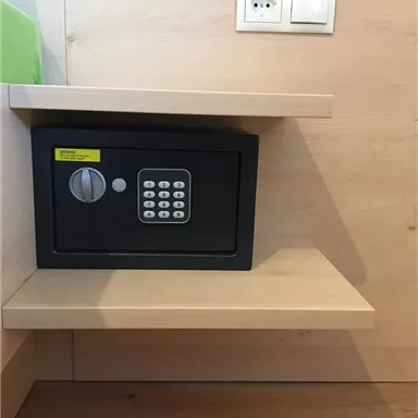 Ein sicherer Schrank mit einem Zahlenschloss steht auf einem Regal. Darüber befindet sich eine Steckdose an der Wand.