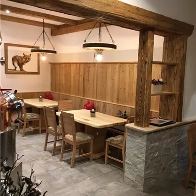 Ein gemütliches Restaurant mit Holzdekor. Es gibt Tische und Stühle sowie eine warme Atmosphäre.