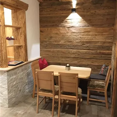 Ein gemütlicher Essbereich mit einem Holztisch und Stühlen. Die Wände sind aus Holz, und es gibt eine sanfte Beleuchtung.