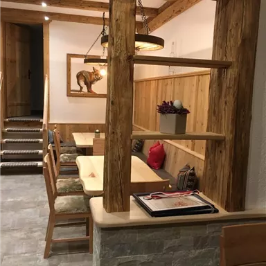 Ein gemütlicher Speisebereich mit Holzregalen und bequemen Stühlen. Der Raum hat warme Farben und eine einladende Atmosphäre.
