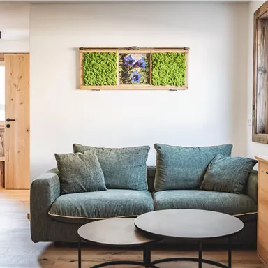 Ein modernes Wohnzimmer mit einem bequemen Sofa und einem runden Couchtisch. Holzelemente und Pflanzen sorgen für eine gemütliche Atmosphäre.