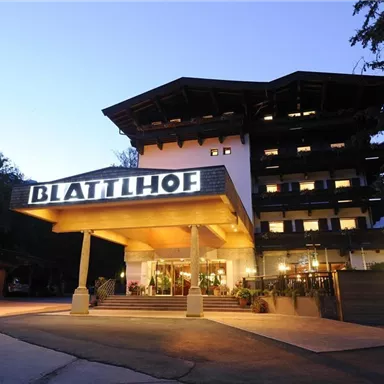 A modern hotel called "Blattlhof" in a picturesque setting. The facade is illuminated and the evening atmosphere is inviting.