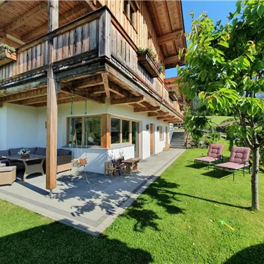 Ein gemütliches Ferienhaus mit Holzverkleidung und einem schönen Garten. Es gibt bequeme Sitzecken und viel Sonnenlicht.