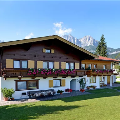A beautiful wooden house with a balcony and colorful flowers. In the background, majestic mountains and a clear sky can be seen.