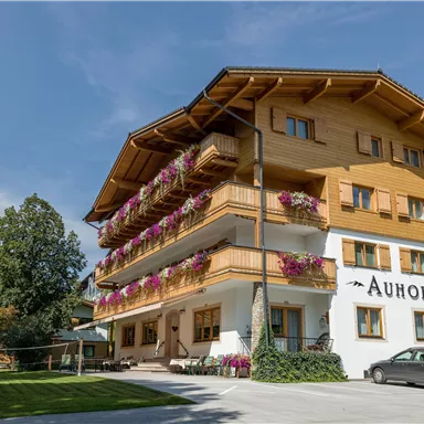A charming wooden building with balconies and colorful flowers. Surrounded by lots of greenery in a peaceful setting.