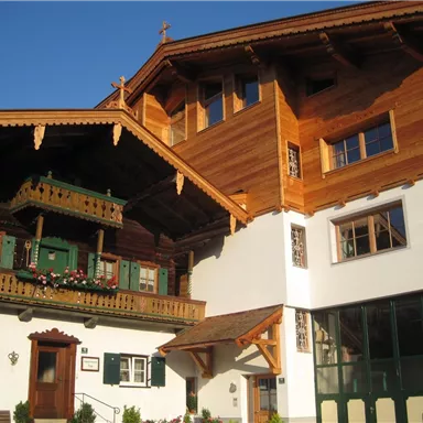 Ein traditionelles Holzhaus mit Balkon und dekorativen Fenstern. Die Architektur ist typisch für die alpine Region.