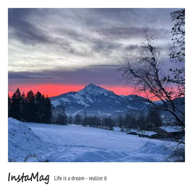 A picturesque winter evening with snow-covered mountains and a glowing red sky. Trees and a hilly landscape complement the peaceful scene.
