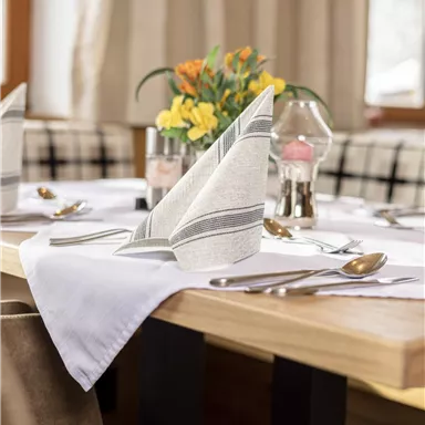 A beautifully set table with elegant napkins and fresh flowers. The atmosphere is inviting and cozy.