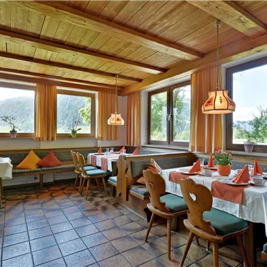 A cozy restaurant with wooden decor and large windows. The tables are adorned with decorative napkins and plants.