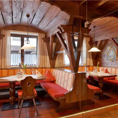 Ein rustikales Restaurant mit Holzverkleidung und gemütlichen Sitzbänken. Die warmen Farben und das einladende Ambiente schaffen eine angenehme Atmosphäre.
