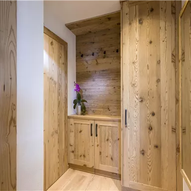 Ein einladender Flur mit Holzvertäfelung und modernen Möbeln. Eine Orchidee verleiht dem Raum eine freundliche Note.