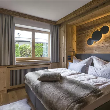 Ein gemütliches Schlafzimmer mit Holzdekor und einem großen Fenster. Die Räume sind hell und einladend, ideal für einen erholsamen Aufenthalt.