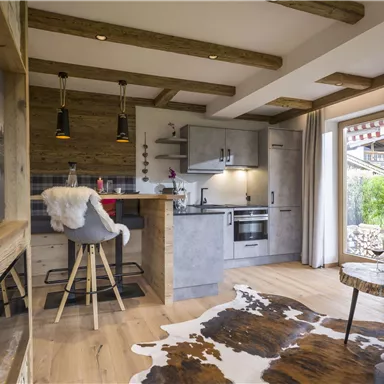 Eine moderne Küche mit Holzverkleidung und stilvollen Möbeln. Der Raum verfügt über große Fenster, die viel Licht hereinlassen.