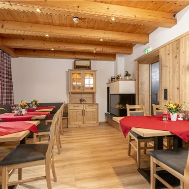 A cozy restaurant with wooden details and red tablecloths. The atmosphere is inviting and warm.