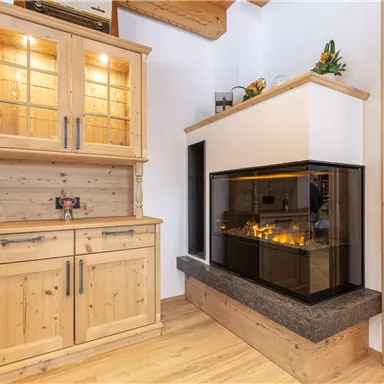 A modern living space with an elegant fireplace and a wooden shelf. The warm wood colors create a cozy atmosphere.