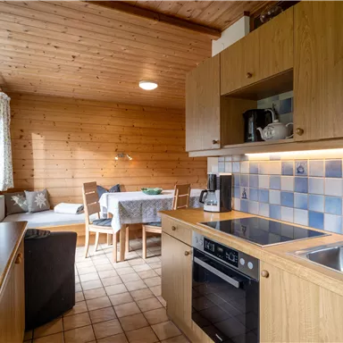 Eine moderne Küche mit Holzverkleidung und blauen Fliesen. Der Raum bietet einen Essbereich und ein gemütliches Ambiente.
