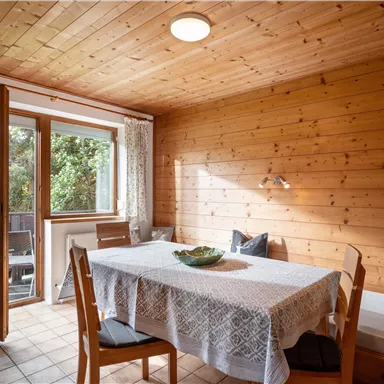 Ein gemütlicher Essbereich mit Holzverkleidung und einem großen Fenster. Der Tisch ist schön gedeckt, und es gibt bequeme Sitzgelegenheiten.