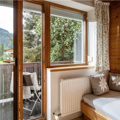 Ein gemütliches Zimmer mit Holzverkleidung und großen Fenstern. Der Blick auf die Berge und die Natur ist wunderschön.