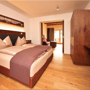 A modern bedroom with a large bed and wooden details. The warm color palette creates a cozy atmosphere.