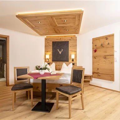 A cozy room with wooden furniture and a round table. The warm atmosphere is emphasized by soft light and rustic decor.
