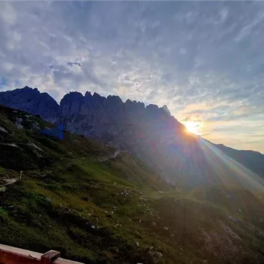 Ein atemberaubender Bergblick mit Sonnenstrahlen, die durch die Wolken scheinen. Die Bergspitzen sind im Hintergrund deutlich sichtbar.