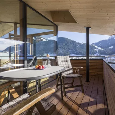 Ein schöner Balkon mit Blick auf die Berge. Am Tisch stehen Getränke und frisches Obst.