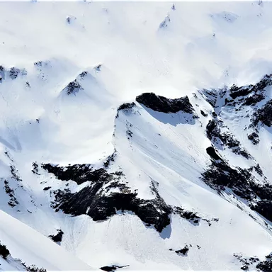 Ein schneebedeckter Berg mit majestätischen Gipfeln und wolkenverhangenem Himmel. Die Landschaft strahlt Ruhe und Unberührtheit aus.