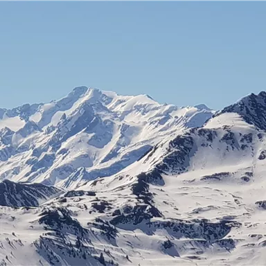 Schneebedeckte Berge unter einem klaren blauen Himmel. Die beeindruckenden Gipfel zeigen eine atemberaubende Winterlandschaft.